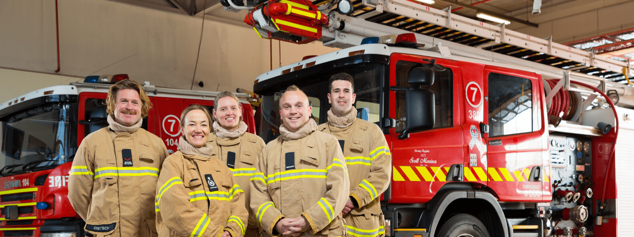 A group of five firefighters in front of a truck 